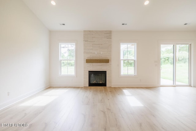 unfurnished living room with a fireplace, light hardwood / wood-style floors, and a healthy amount of sunlight