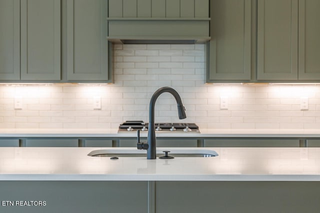 kitchen featuring sink, green cabinetry, and tasteful backsplash