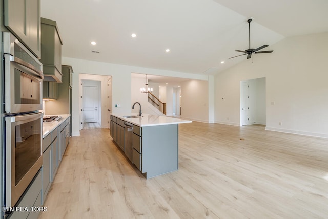 kitchen featuring stainless steel double oven, a center island with sink, sink, lofted ceiling, and light hardwood / wood-style flooring