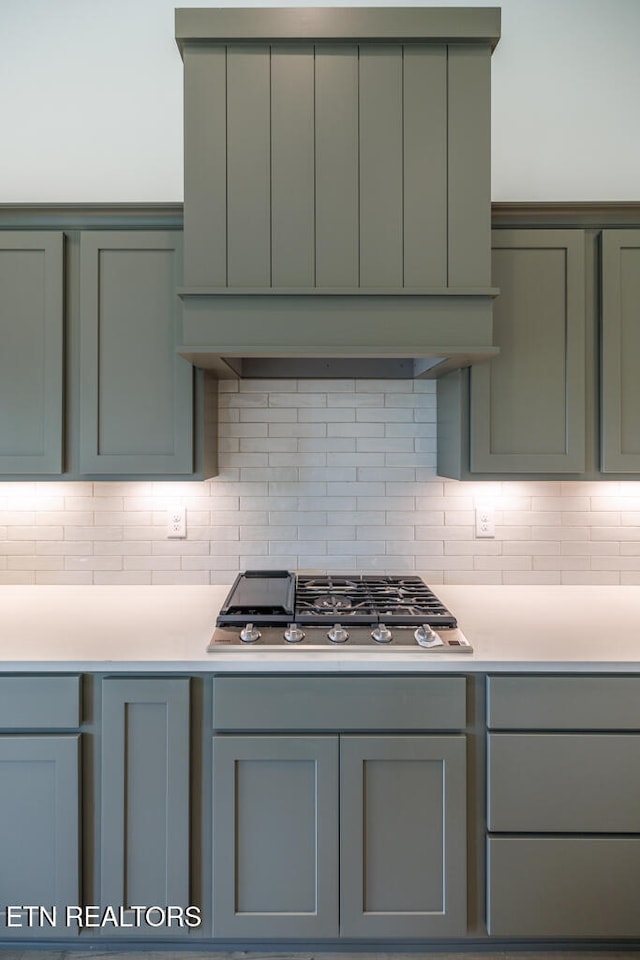 kitchen with stainless steel gas cooktop, green cabinets, and backsplash