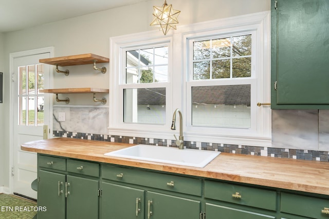 kitchen with green cabinetry, sink, tasteful backsplash, and wood counters