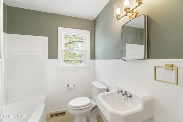 bathroom featuring toilet, a bath, sink, and tile walls