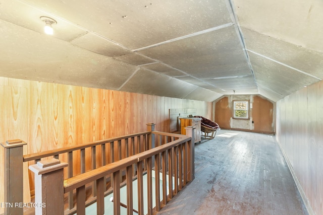 additional living space with wooden walls, hardwood / wood-style floors, and vaulted ceiling