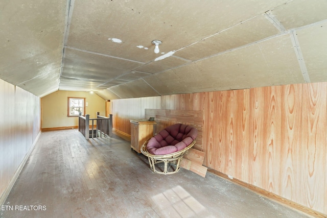 additional living space featuring hardwood / wood-style floors, lofted ceiling, and wooden walls