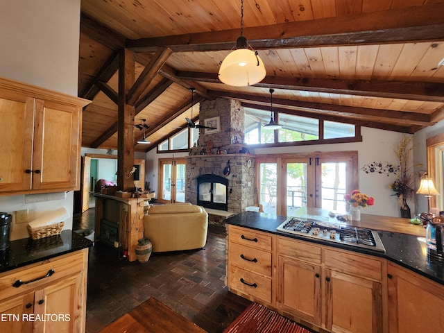 kitchen with beam ceiling, a stone fireplace, wood ceiling, stainless steel gas stovetop, and french doors