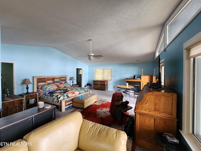 bedroom featuring ceiling fan, a textured ceiling, carpet floors, multiple windows, and vaulted ceiling