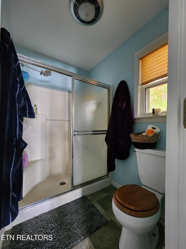 bathroom featuring a shower with door, tile patterned floors, and toilet