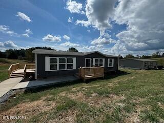 rear view of property with a wooden deck and a lawn