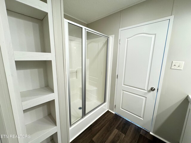 bathroom featuring wood-type flooring, a textured ceiling, and a shower with door