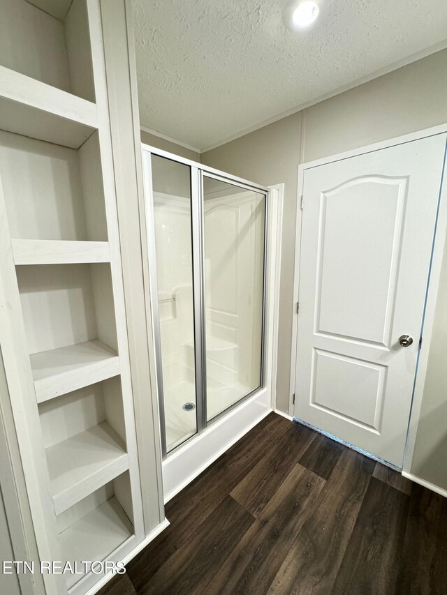 bathroom with hardwood / wood-style flooring, a shower with shower door, and a textured ceiling