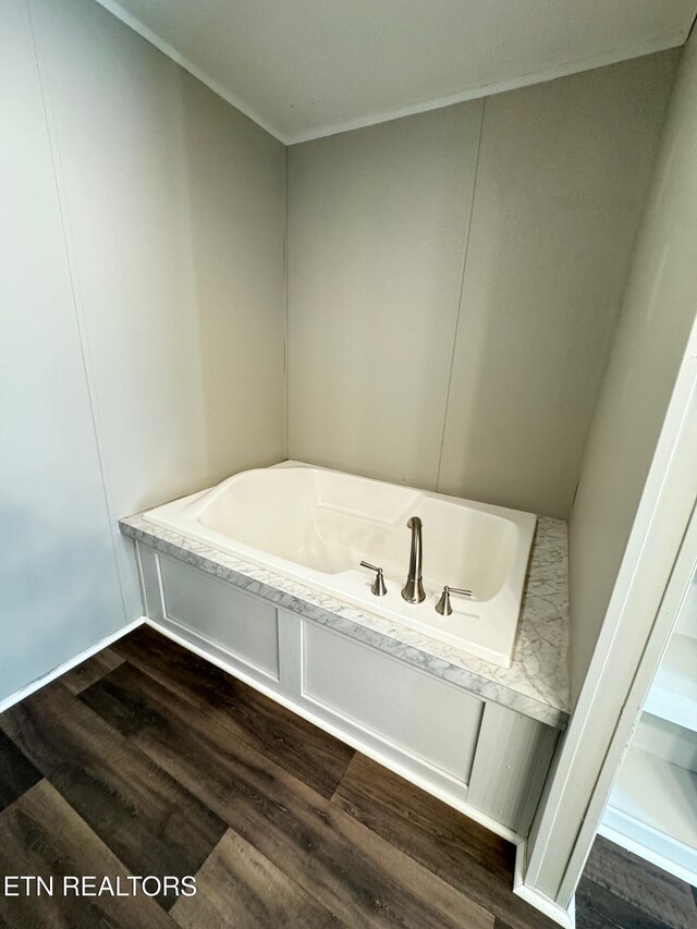 bathroom with a bathing tub, hardwood / wood-style floors, and ornamental molding