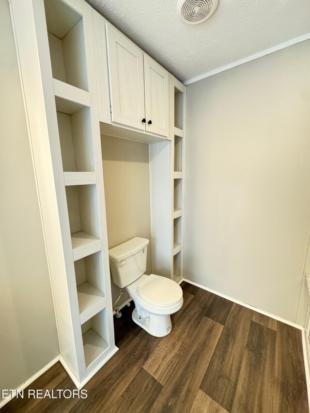 bathroom with hardwood / wood-style floors, a textured ceiling, and toilet