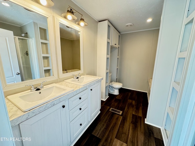 bathroom featuring hardwood / wood-style flooring, a textured ceiling, vanity, an enclosed shower, and toilet