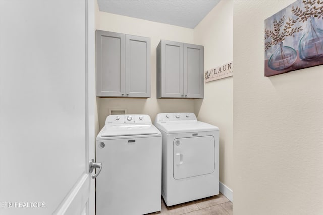 laundry room featuring cabinets, independent washer and dryer, a textured ceiling, and light tile patterned floors