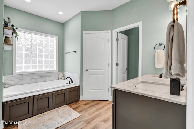 bathroom with a tub, vanity, and hardwood / wood-style flooring