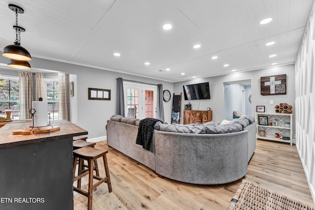 living room with french doors, crown molding, and light hardwood / wood-style flooring