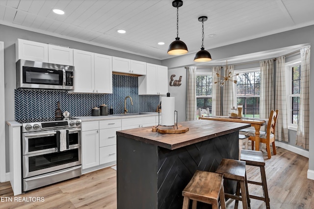 kitchen featuring wood counters, stainless steel appliances, pendant lighting, light hardwood / wood-style flooring, and a kitchen island