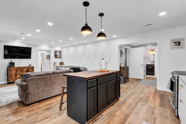 kitchen featuring a center island, pendant lighting, stainless steel range with electric stovetop, a breakfast bar, and light wood-type flooring