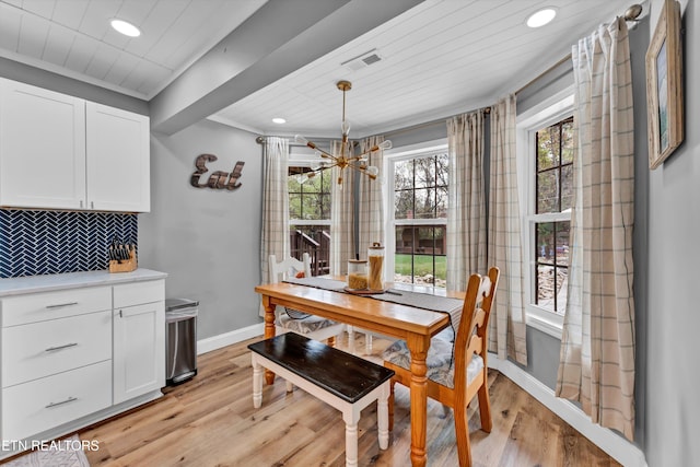 dining area featuring light hardwood / wood-style flooring, plenty of natural light, a notable chandelier, and crown molding