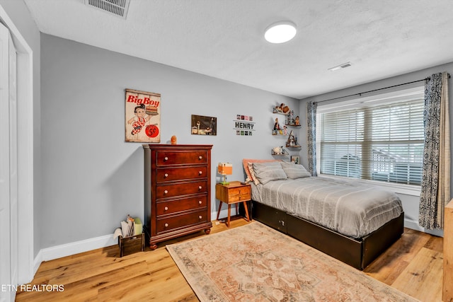 bedroom featuring a textured ceiling and light hardwood / wood-style floors