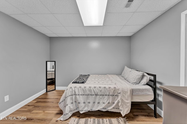 bedroom with a paneled ceiling and light hardwood / wood-style flooring