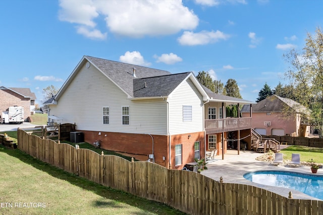 rear view of property with a swimming pool side deck, a patio, and a yard