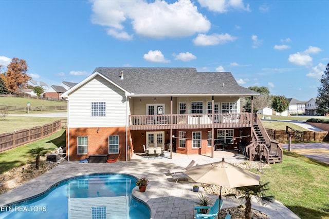 rear view of property with a yard, a swimming pool side deck, french doors, and a patio