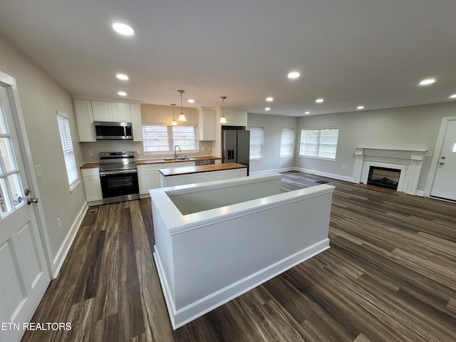 kitchen featuring white cabinets, stainless steel appliances, dark hardwood / wood-style floors, and decorative light fixtures