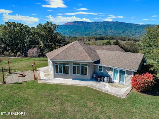 back of house with a patio, a mountain view, and a yard