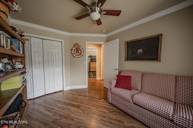 living room with dark wood-type flooring, ceiling fan, and crown molding