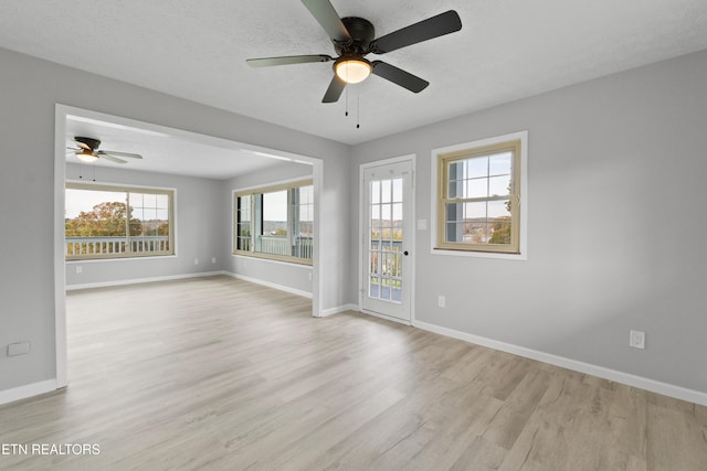 empty room with light hardwood / wood-style floors, a textured ceiling, and ceiling fan