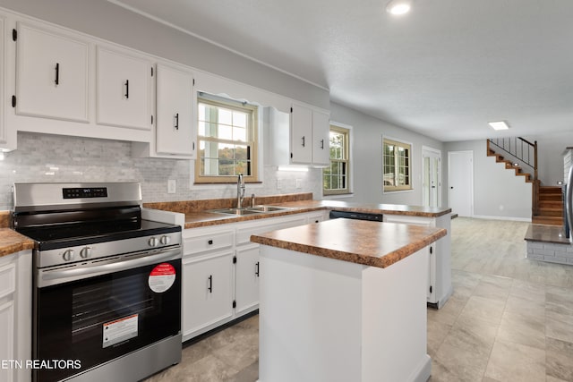 kitchen with stainless steel appliances, white cabinetry, backsplash, sink, and a center island
