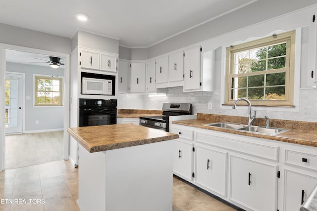kitchen featuring black oven, a healthy amount of sunlight, sink, and a center island