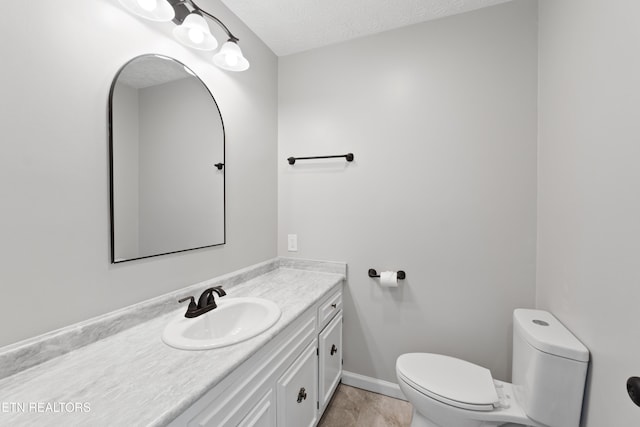 bathroom with toilet, vanity, a textured ceiling, and tile patterned flooring