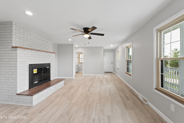 unfurnished living room featuring a fireplace, ceiling fan, and light hardwood / wood-style flooring