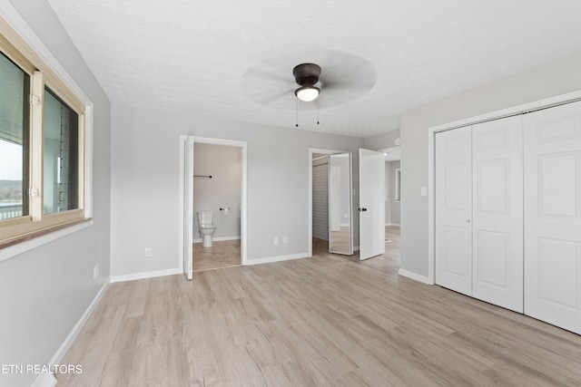 unfurnished bedroom with ceiling fan, a textured ceiling, light hardwood / wood-style floors, and ensuite bath