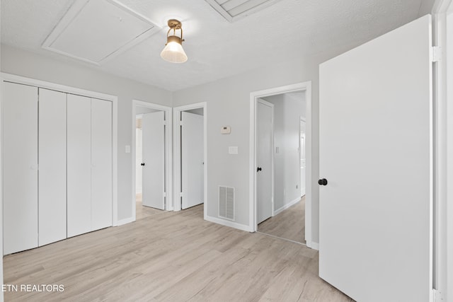 unfurnished bedroom featuring a closet, a textured ceiling, and light hardwood / wood-style floors