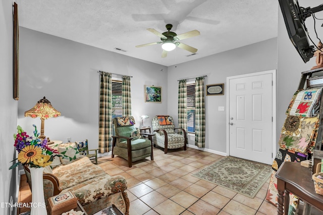 interior space featuring ceiling fan, light tile patterned flooring, and a textured ceiling