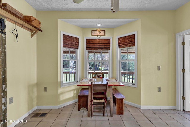 dining space featuring plenty of natural light, light tile patterned flooring, and a textured ceiling