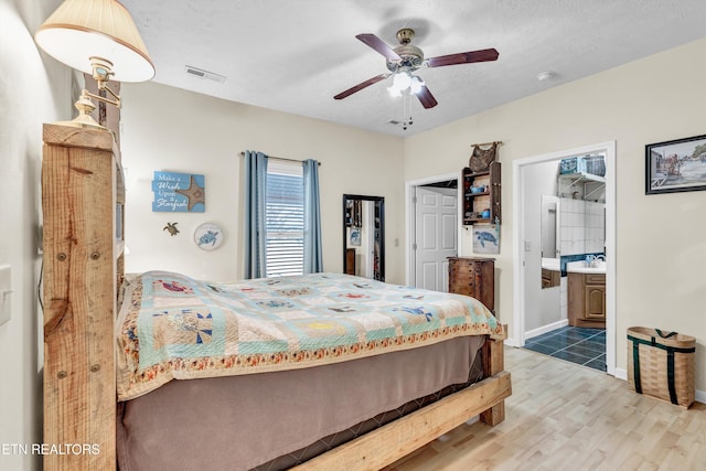 bedroom featuring ensuite bath, ceiling fan, a textured ceiling, and hardwood / wood-style flooring