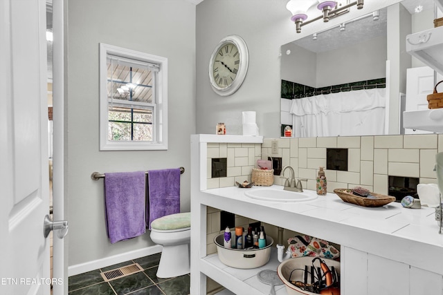 bathroom with tile patterned flooring, toilet, sink, and backsplash