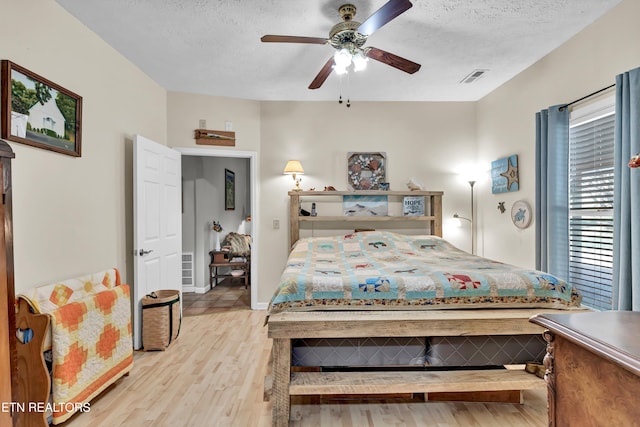 bedroom featuring ceiling fan, light hardwood / wood-style floors, and a textured ceiling