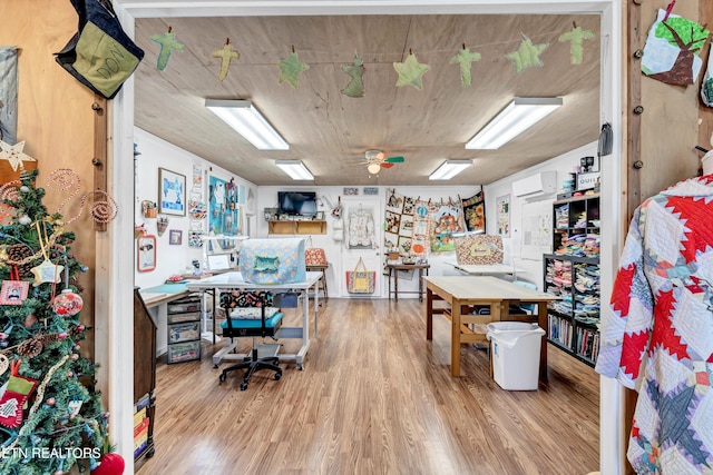 office featuring ceiling fan, a wall unit AC, and light hardwood / wood-style flooring