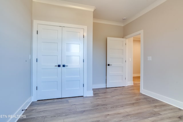 unfurnished bedroom with light hardwood / wood-style floors, crown molding, and a closet