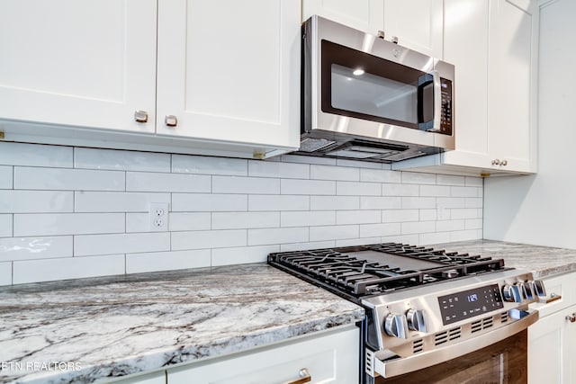 kitchen featuring backsplash, white cabinets, light stone counters, and stainless steel appliances