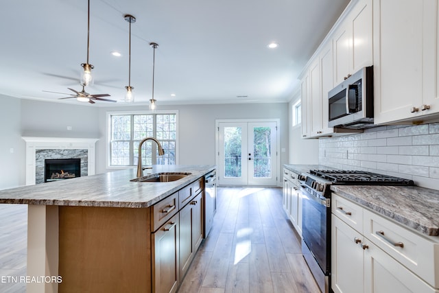 kitchen featuring stainless steel appliances, white cabinetry, and a center island with sink