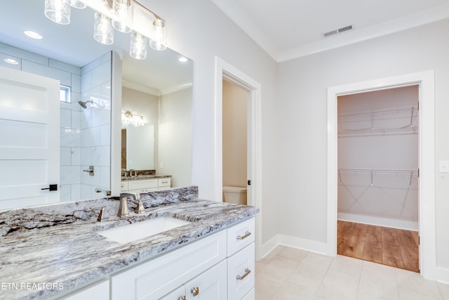 bathroom featuring ornamental molding, vanity, tiled shower, tile patterned floors, and toilet