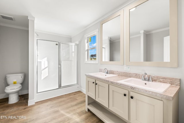 bathroom featuring toilet, hardwood / wood-style flooring, ornamental molding, vanity, and a shower with shower door