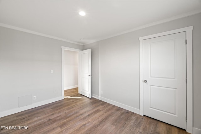 unfurnished bedroom with hardwood / wood-style floors and ornamental molding