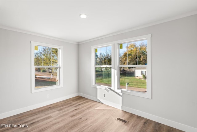 empty room featuring light wood-type flooring and crown molding